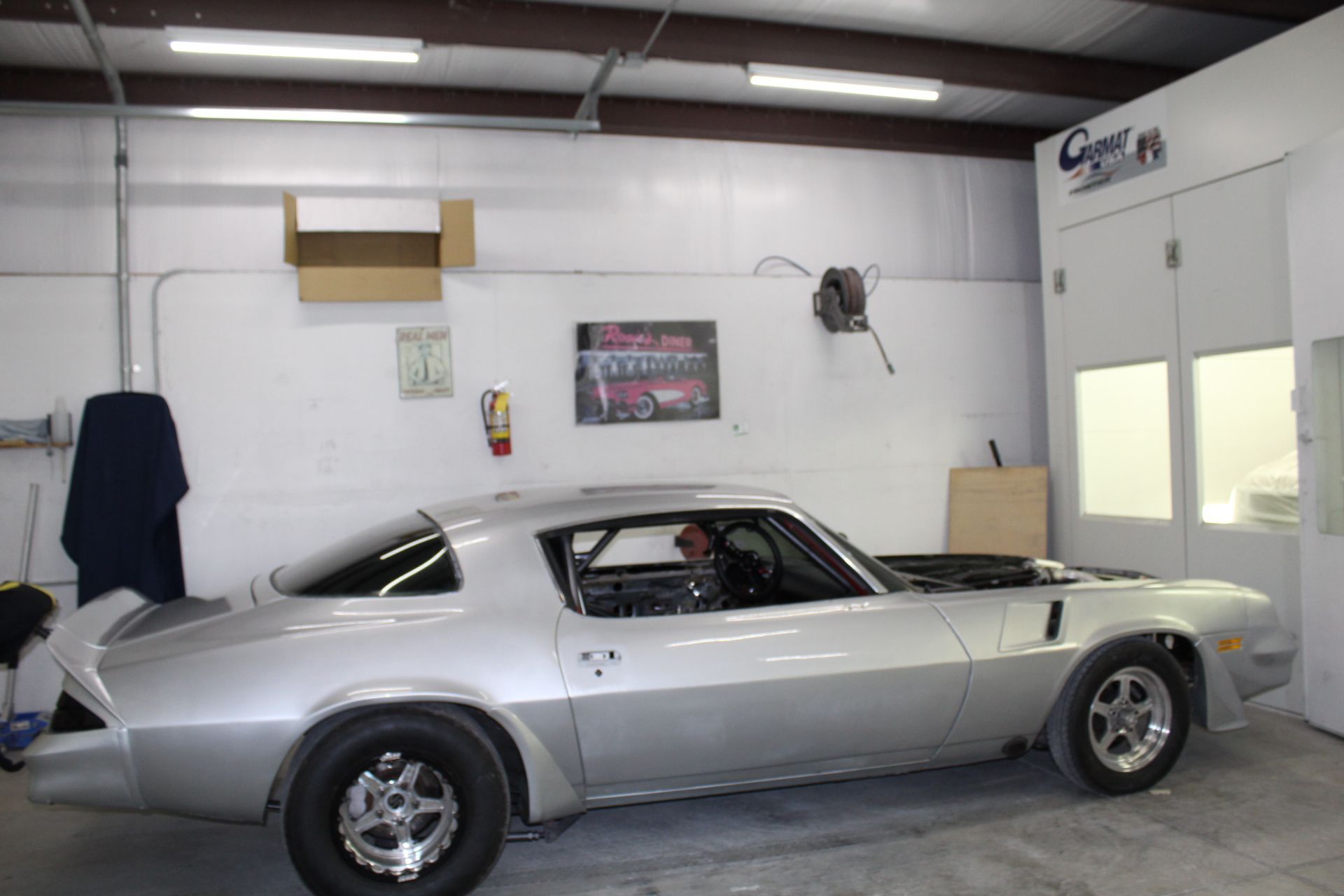 A silver muscle car is parked in a garage