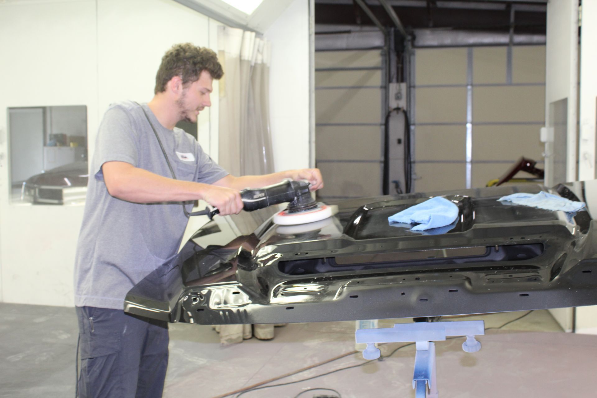 A man is polishing a car with a machine in a garage.