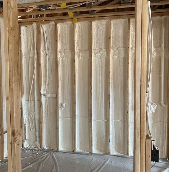 Interior wall construction with spray foam insulation, exposed wooden beams.