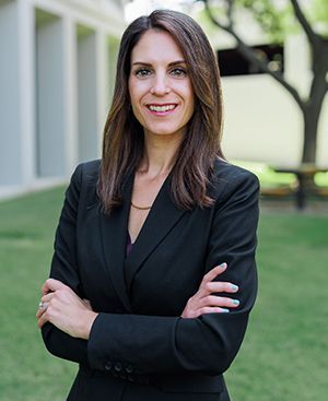 Annalise Lang in a black suit is posing for a picture with her arms crossed.