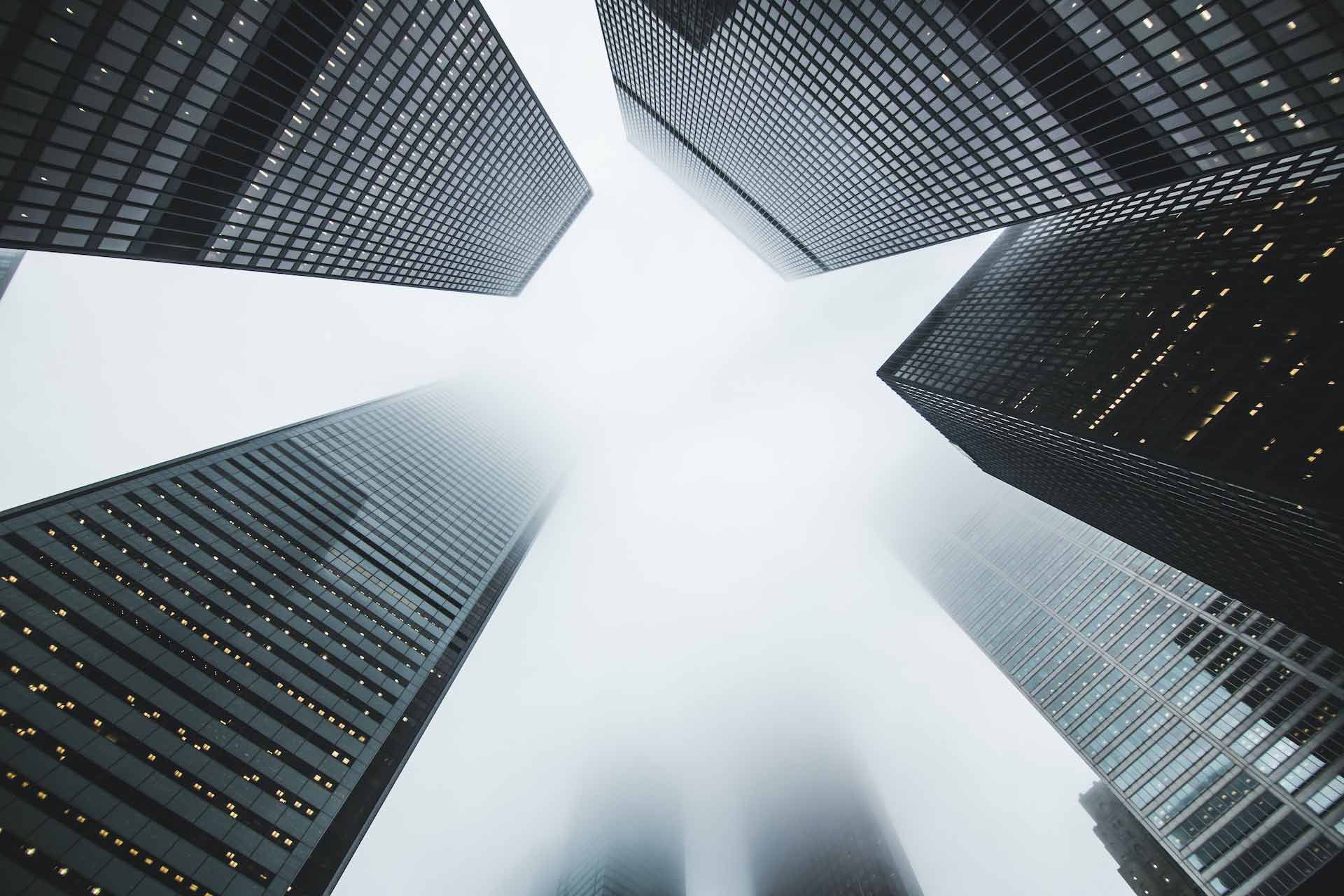 Looking up at a group of tall buildings in the fog