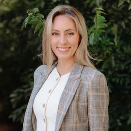 Emily Gipson in a plaid jacket and white shirt is smiling for the camera.