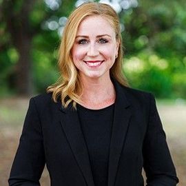 Mara Davidson in a black jacket and black shirt is smiling for the camera.
