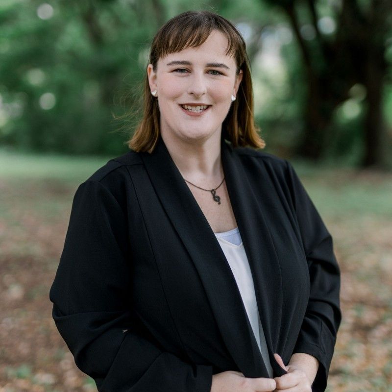 Shannon Humenesky in a black jacket and white shirt is smiling for the camera.