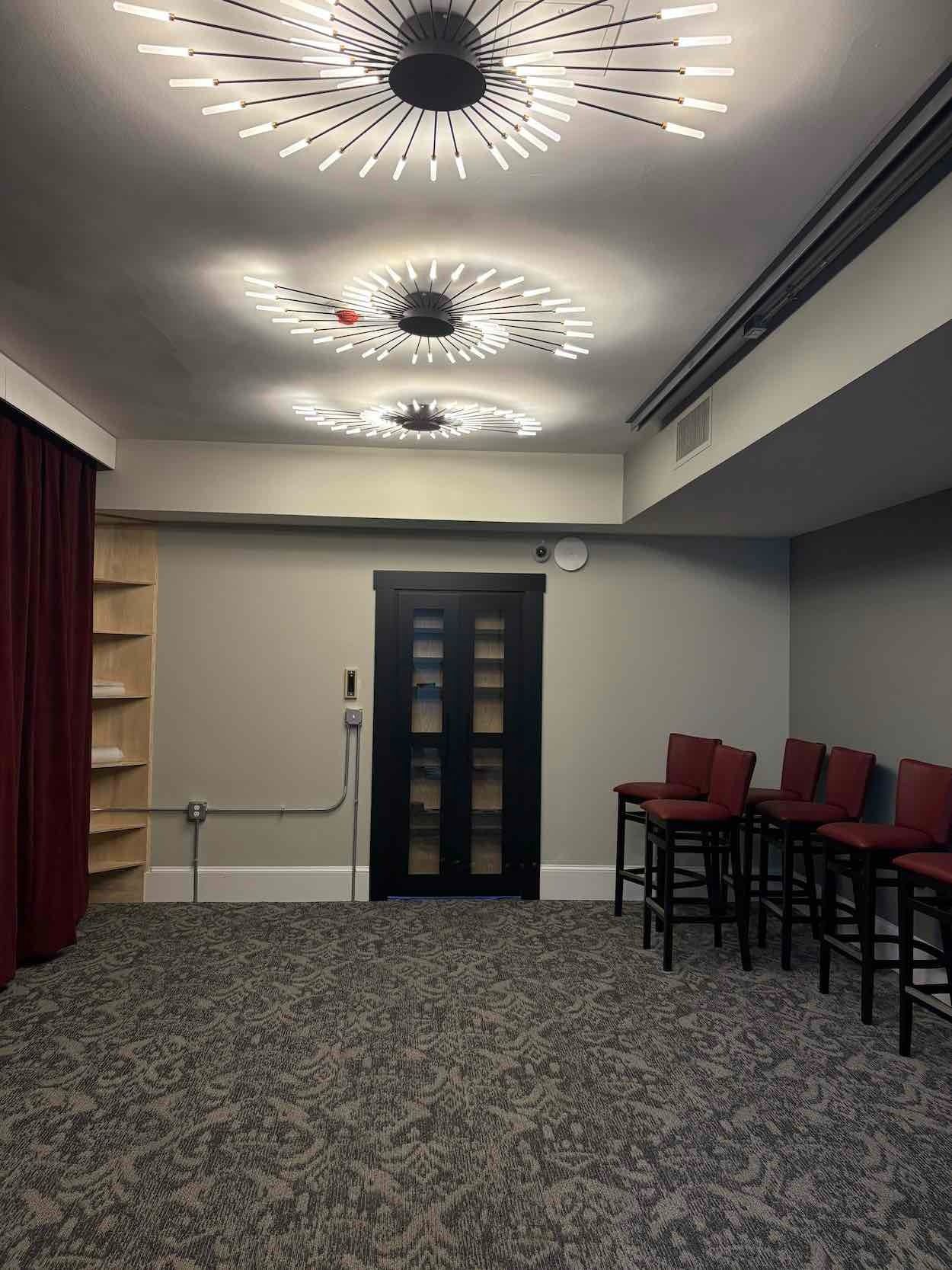 An interior room with a door, shelves, seating, and decorative ceiling lights.