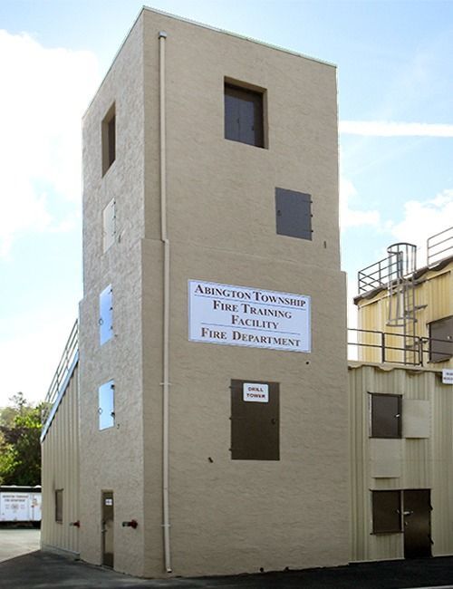 Fire training tower with tan exterior, doors, and windows; sign reads 