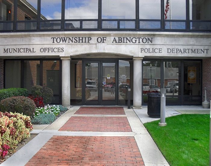 Township of Abington Municipal Offices and Police Department building exterior. Brick facade, glass doors, landscaping.