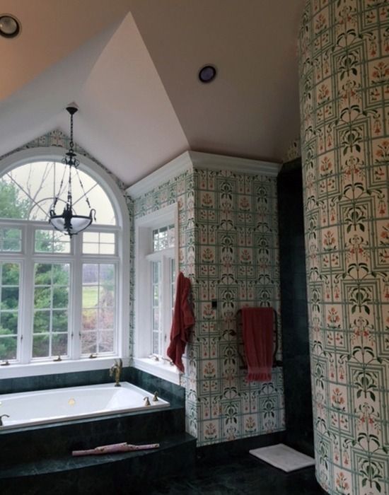 Bathroom with green patterned wallpaper, arched window, and a bathtub.