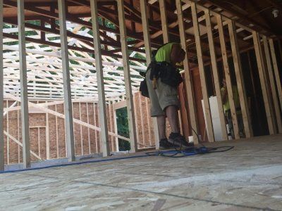 Construction worker installing wiring in a framed house interior under construction