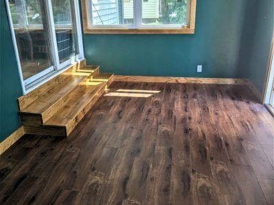 Empty room with dark wood floors, teal walls, and built-in wooden steps by a sliding glass door.