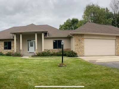 Single-story beige house with a front lawn and attached two-car garage under a cloudy sky