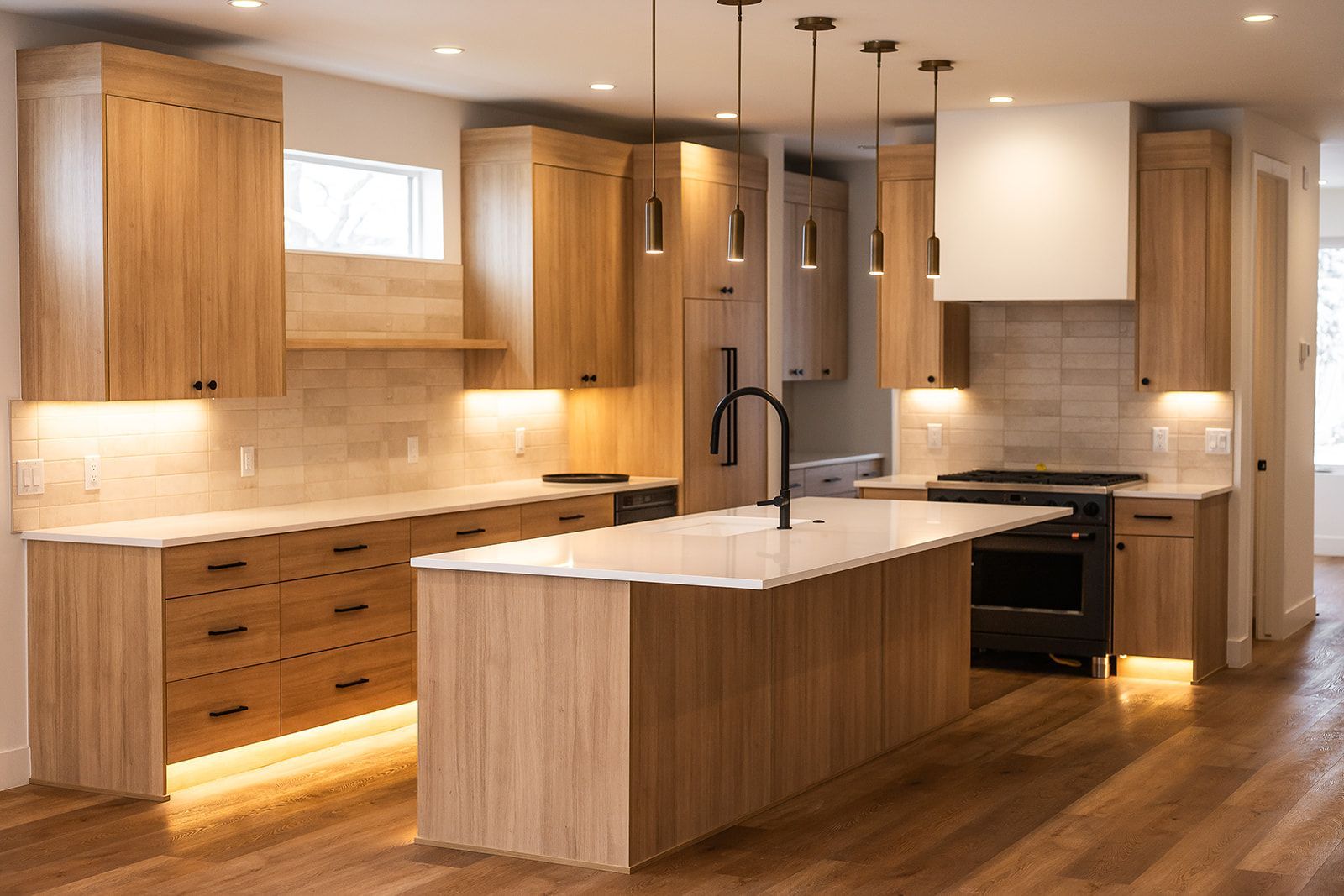 Modern kitchen with light wood cabinets, white countertops, and an island.
