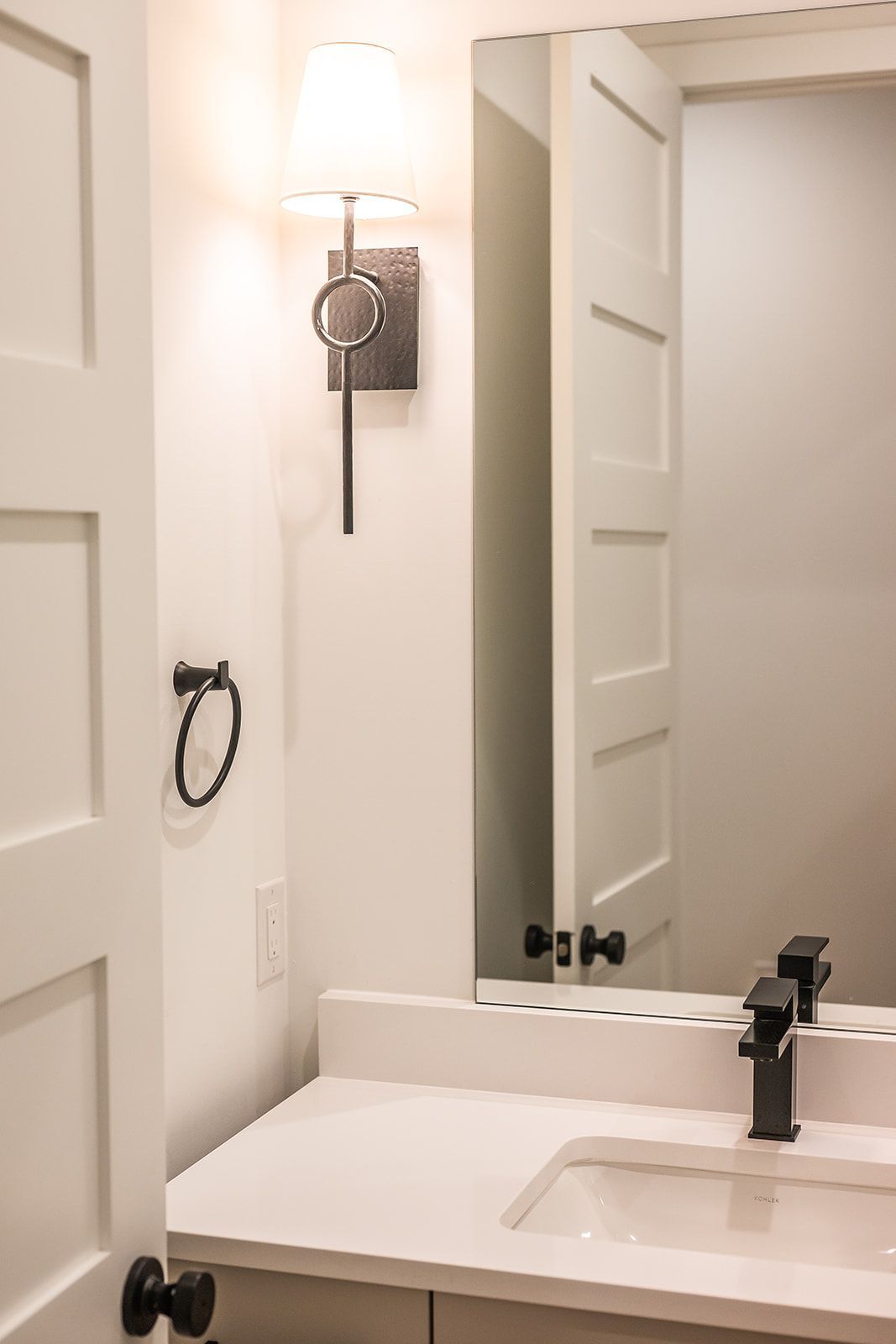 Bathroom with white walls, mirror, and a black faucet.