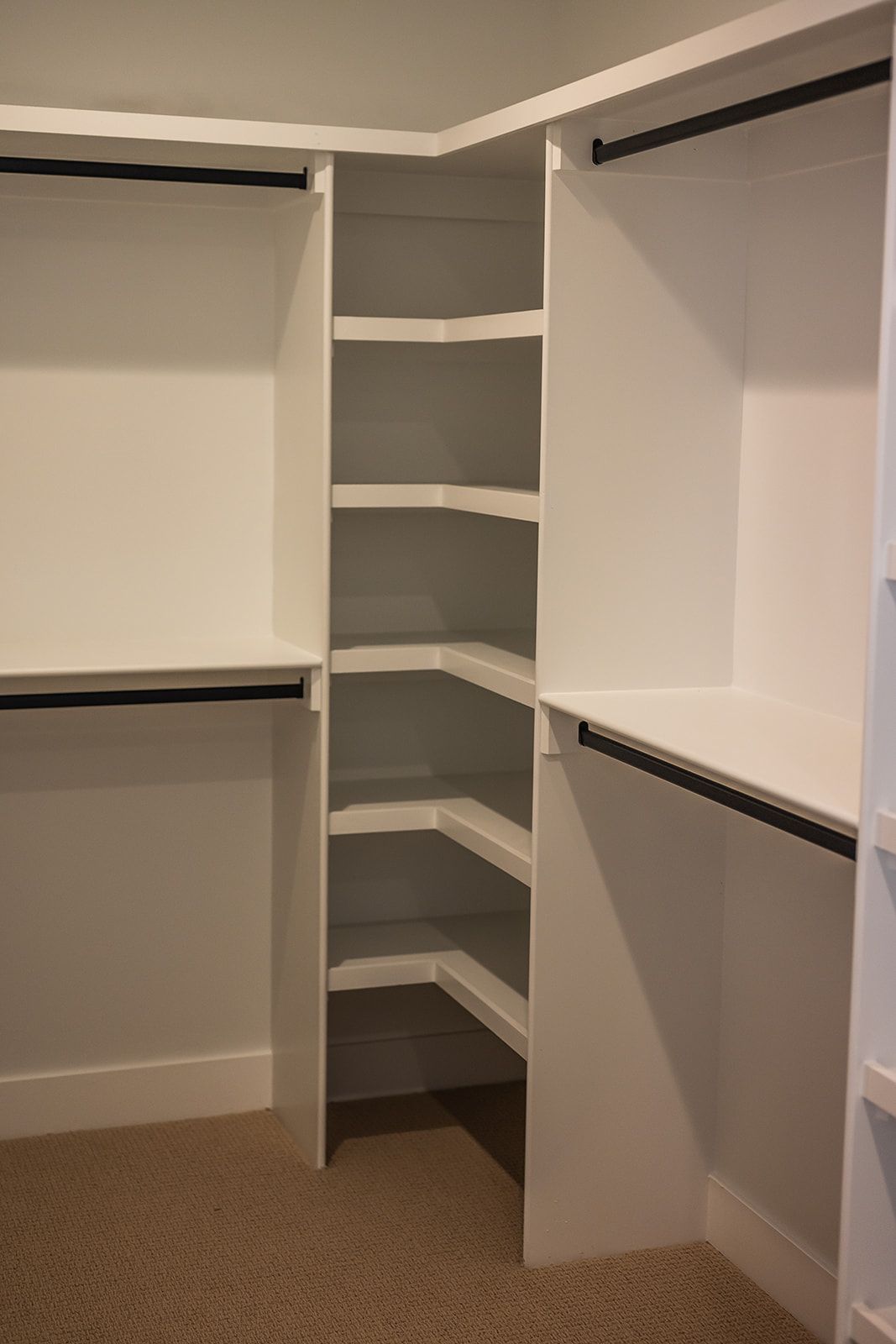 White built-in closet with shelves and hanging rods; carpeted floor.
