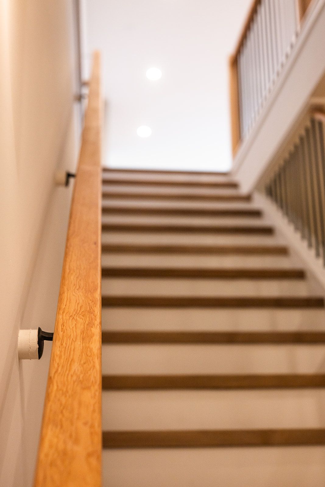 Wooden staircase with a wooden handrail, white risers, and a focus on ascent.