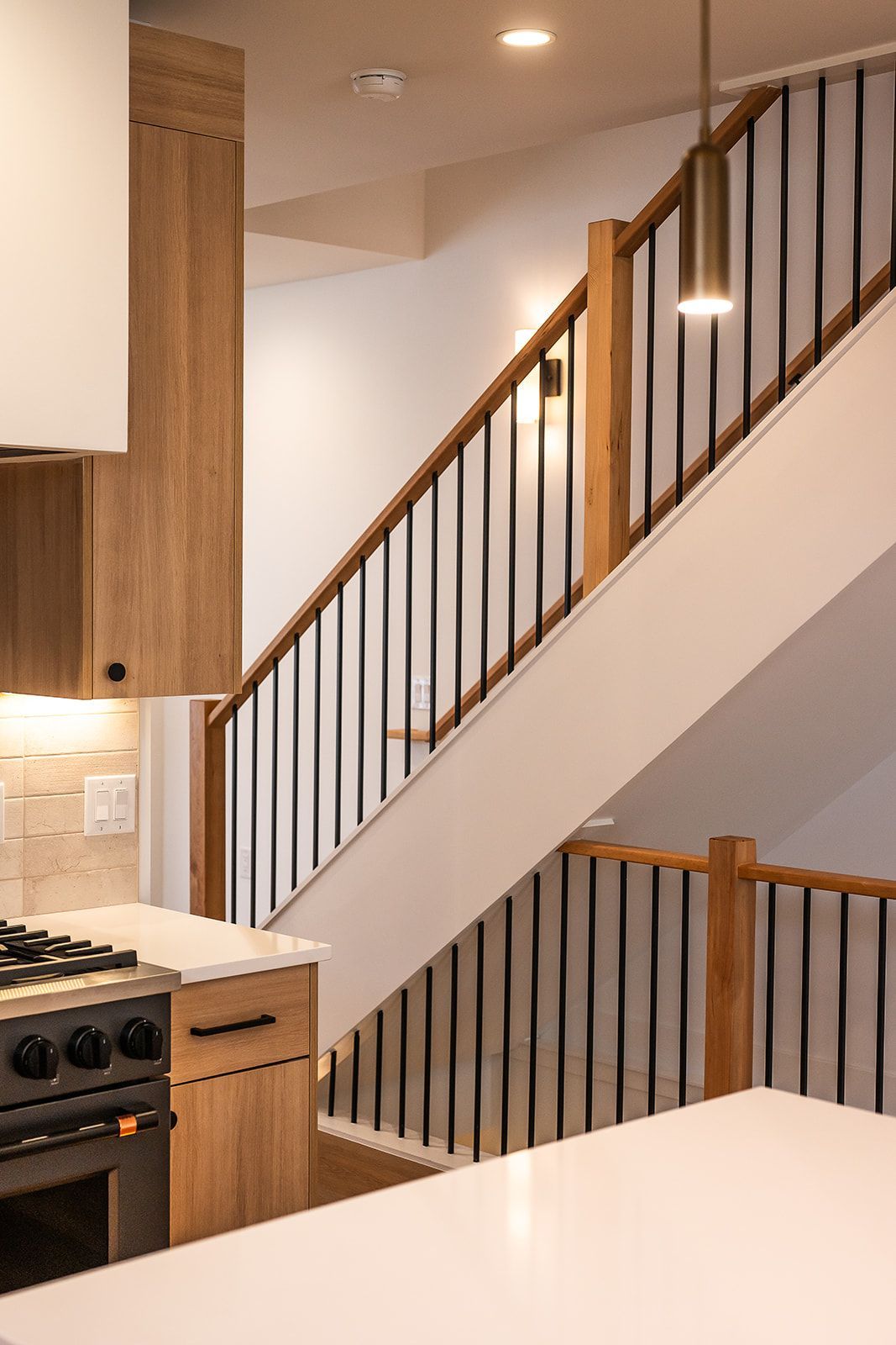 Kitchen with wooden cabinets and stairs with black metal railings.