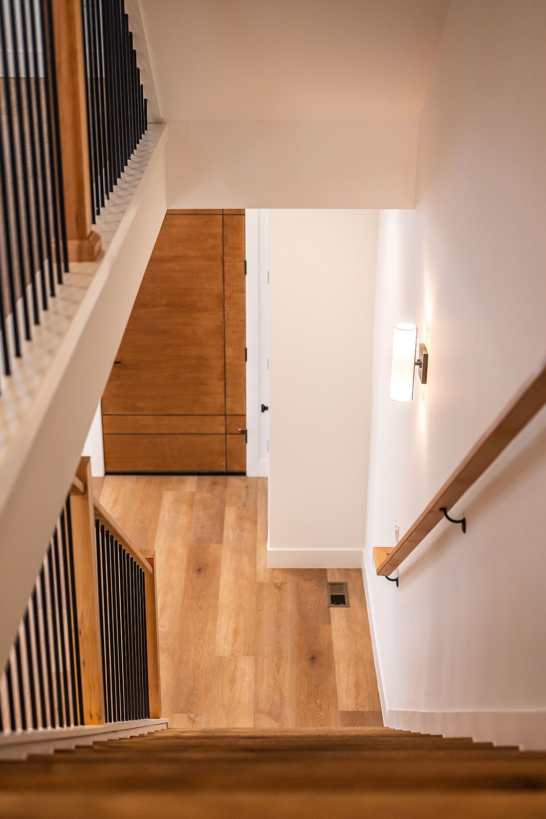 Staircase interior with wooden steps, white walls, and black metal railing.