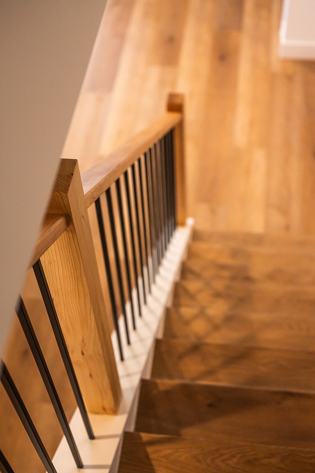 Wooden staircase with black metal railings, viewed from above.