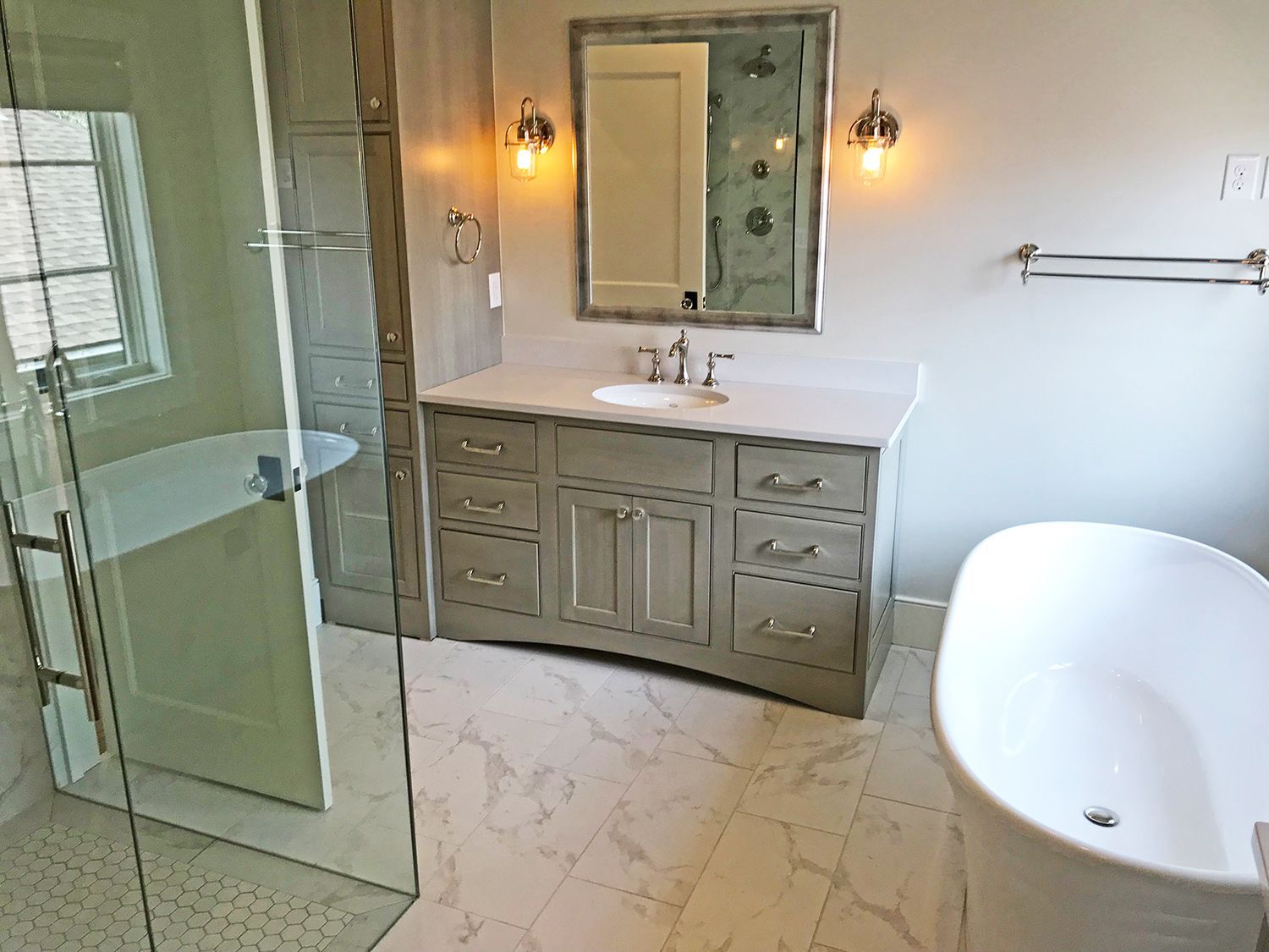 Bathroom with freestanding tub, vanity, shower, and marble tile floor. Light grey and white color scheme.