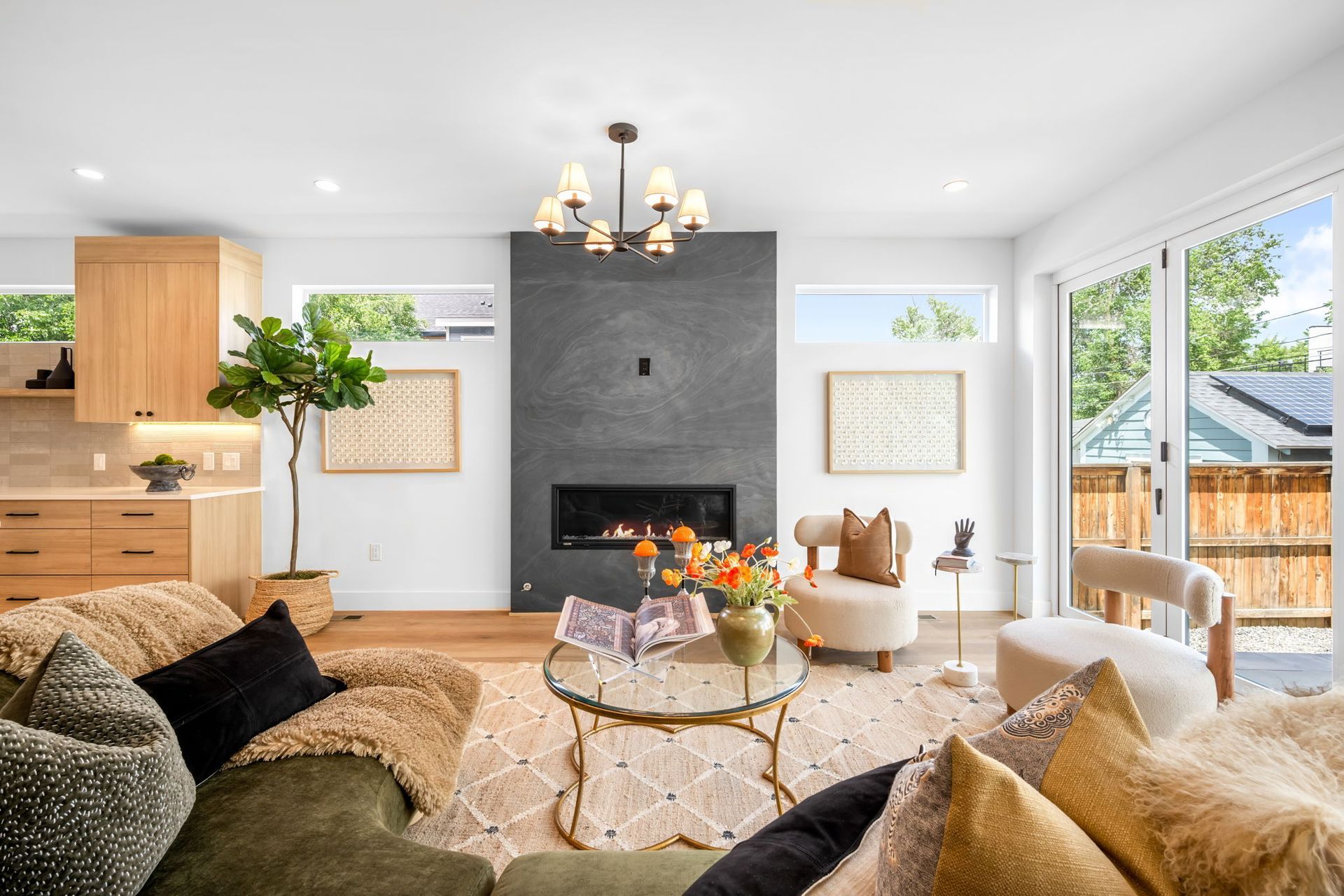 Modern living room with fireplace, green sofa, wooden floors, and large windows.