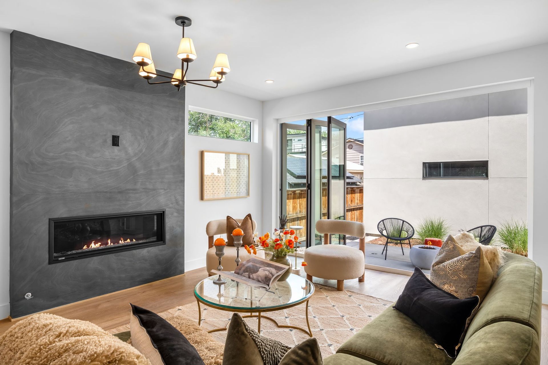 Modern living room with fireplace, green sofa, and glass door leading to patio.