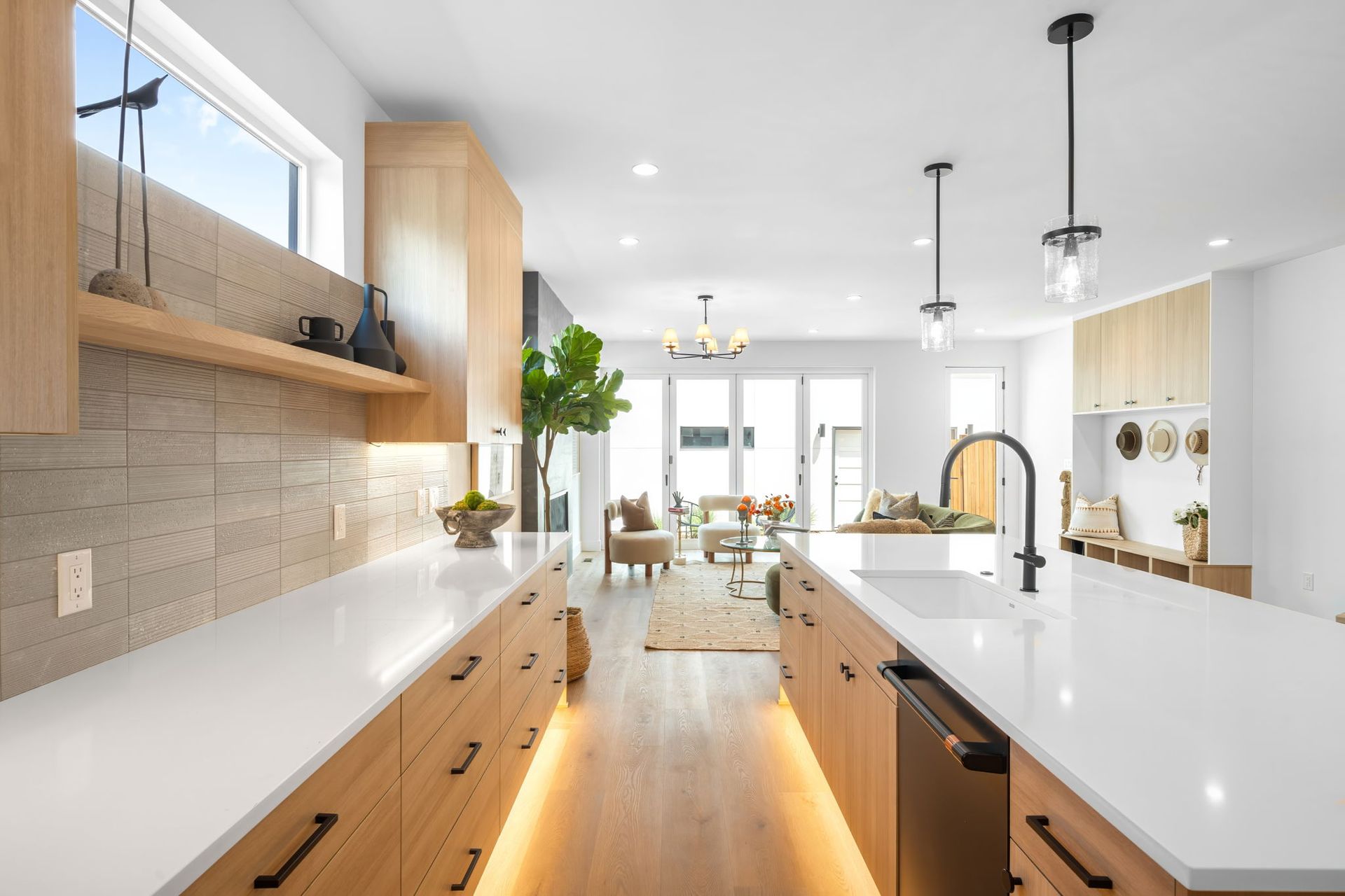 Modern kitchen with wood cabinets, white countertops, and island. Natural light floods the space.