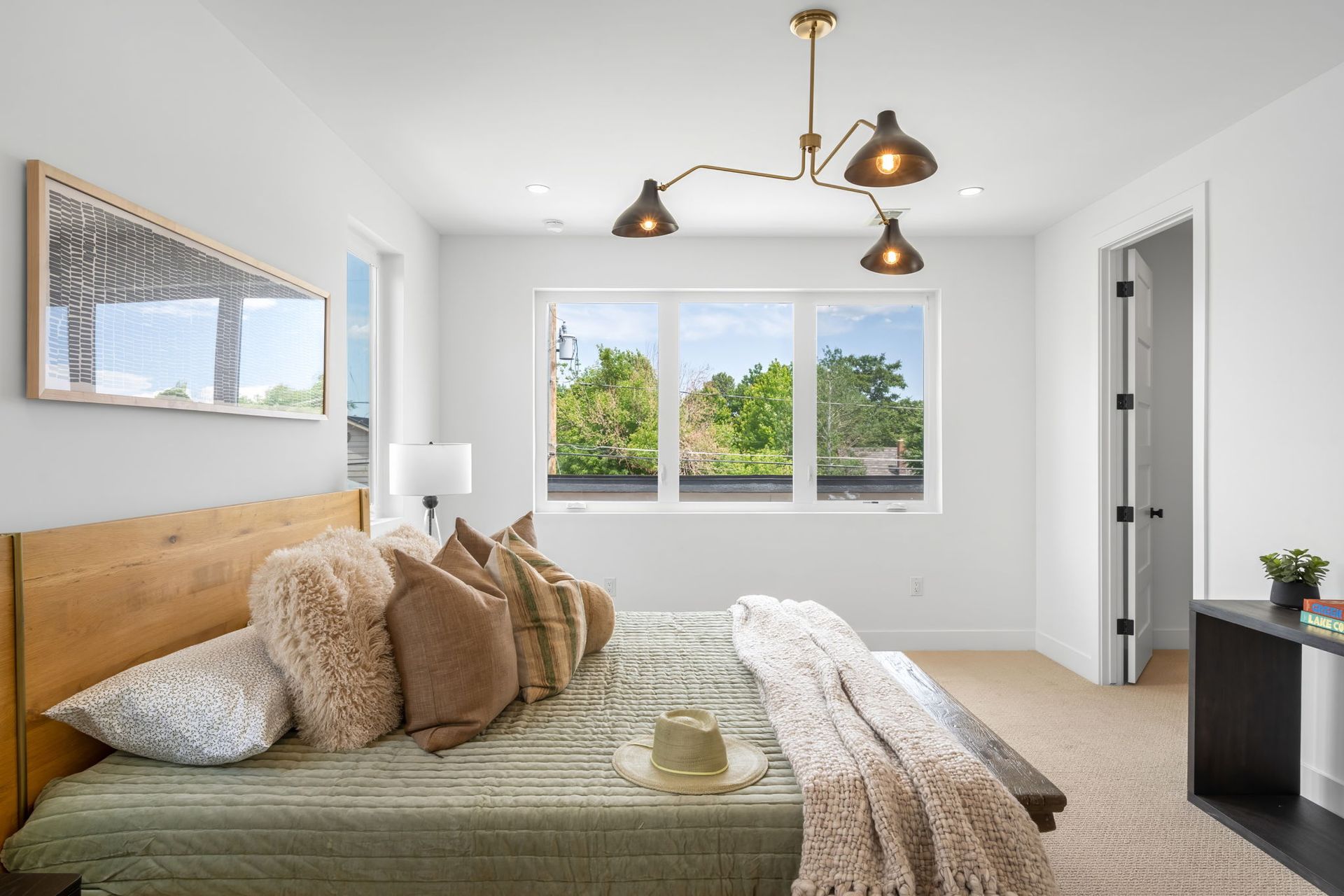 Bedroom with wood bed, window, neutral color scheme, and hanging light fixture.