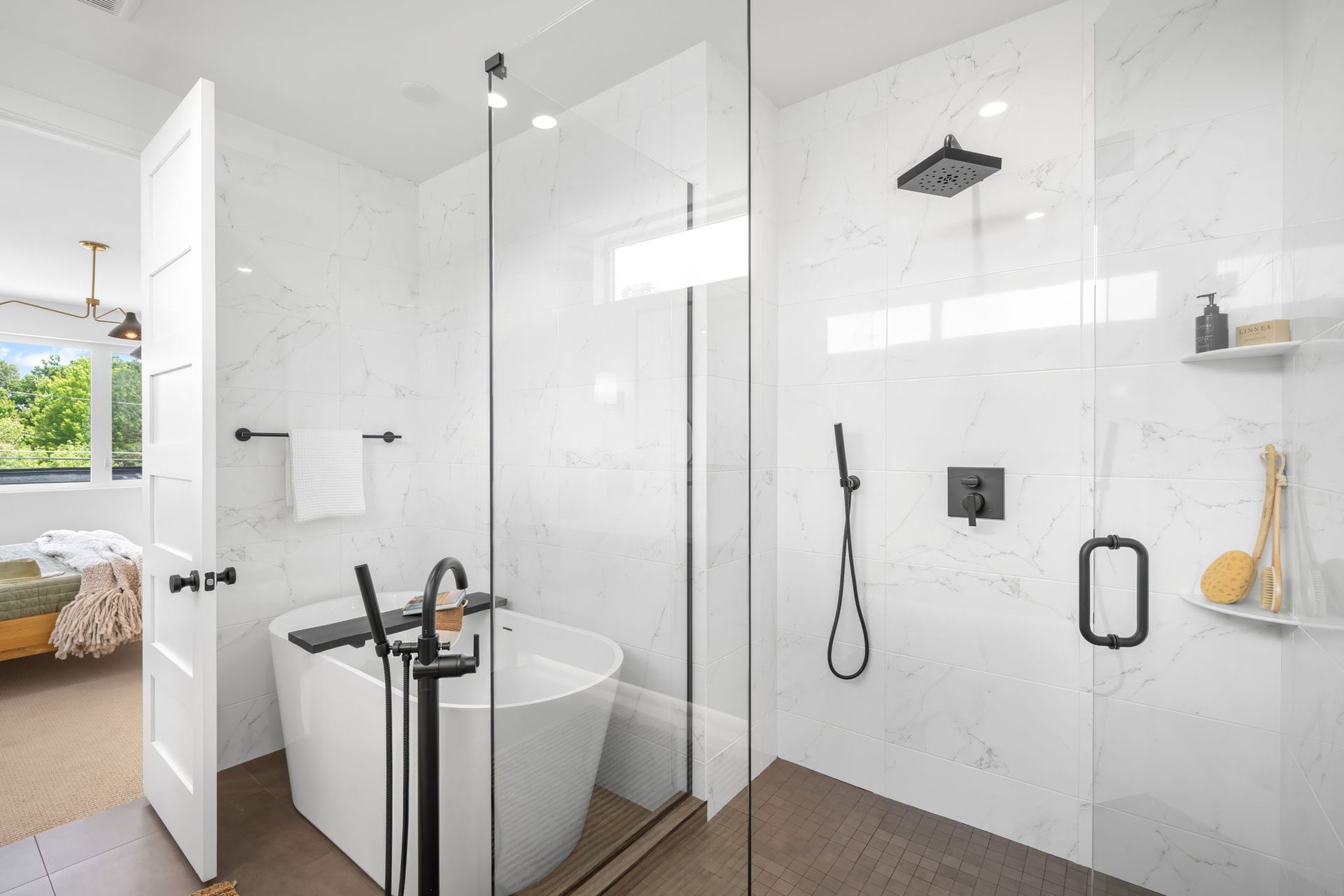 Modern white bathroom with a glass shower, a freestanding tub, and a partially open door.