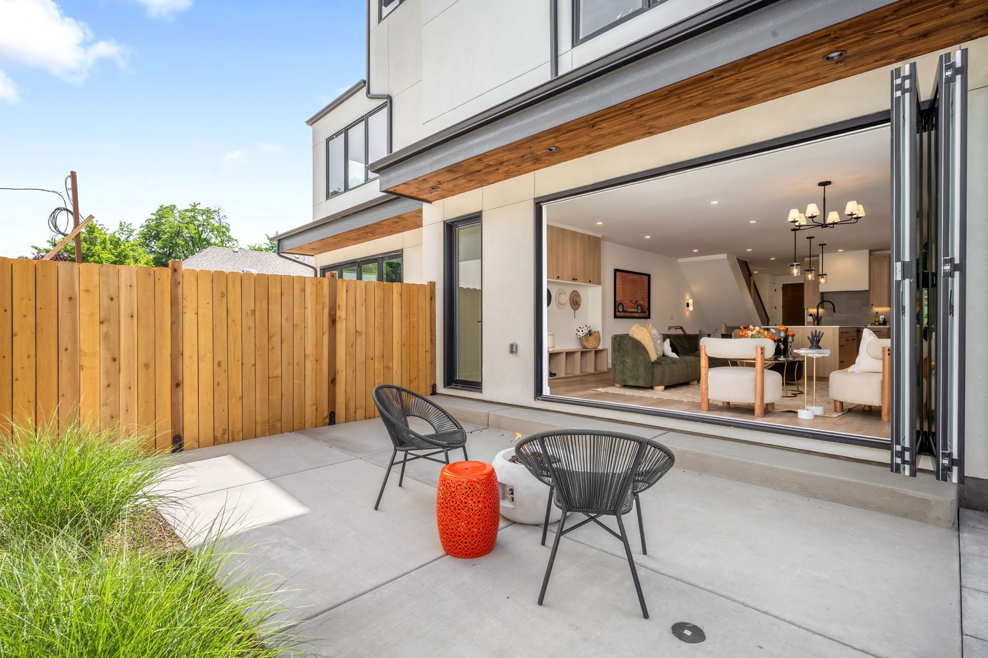 Back patio with black chairs, orange stool, open door to living area.