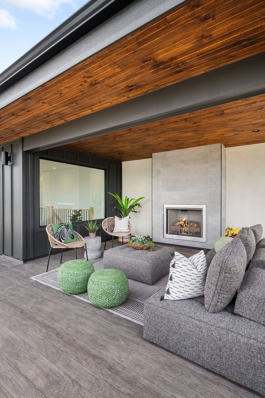 Outdoor patio with gray sofa, fireplace, and wood ceiling.