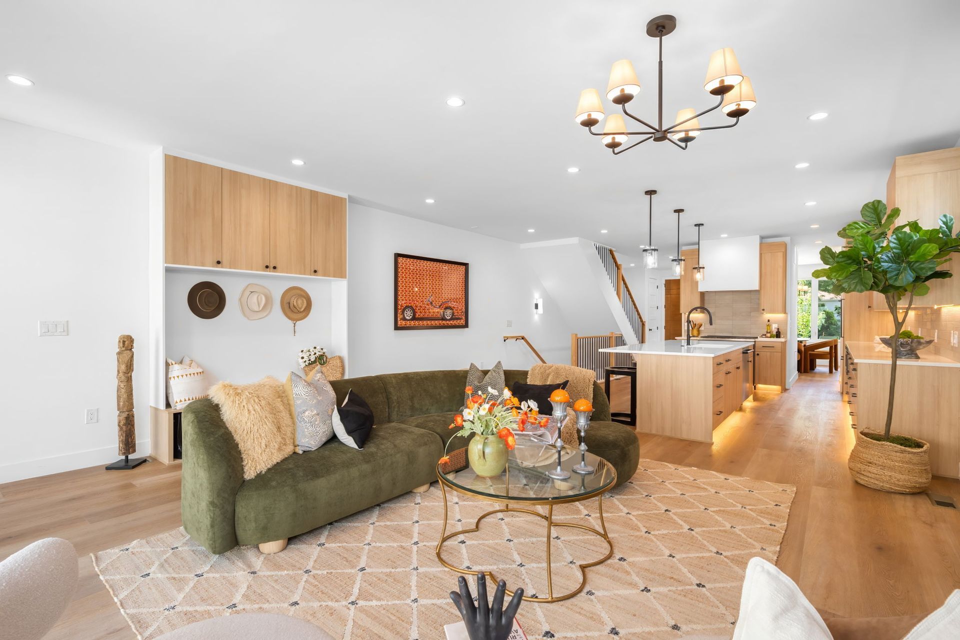 Living room with green sofa, wooden cabinets, and a kitchen visible in the background.