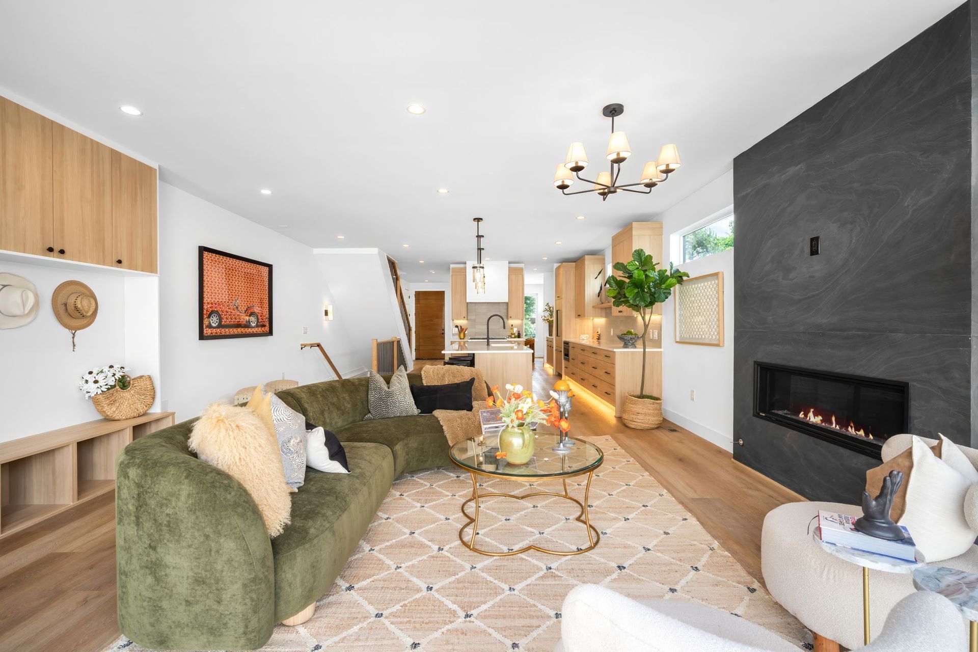 A modern living room with green sofa, fireplace, and open kitchen.