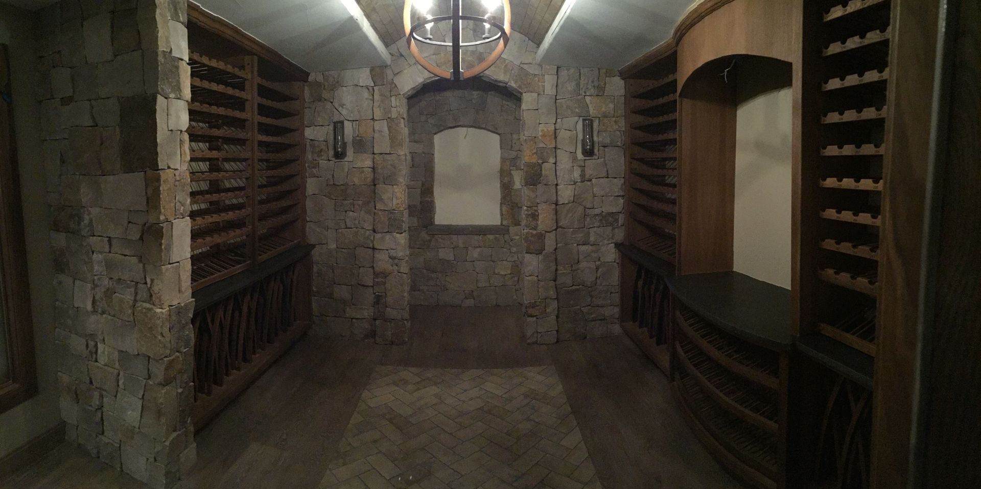 Wine cellar with stone walls, wooden racks for bottles, and ambient lighting.