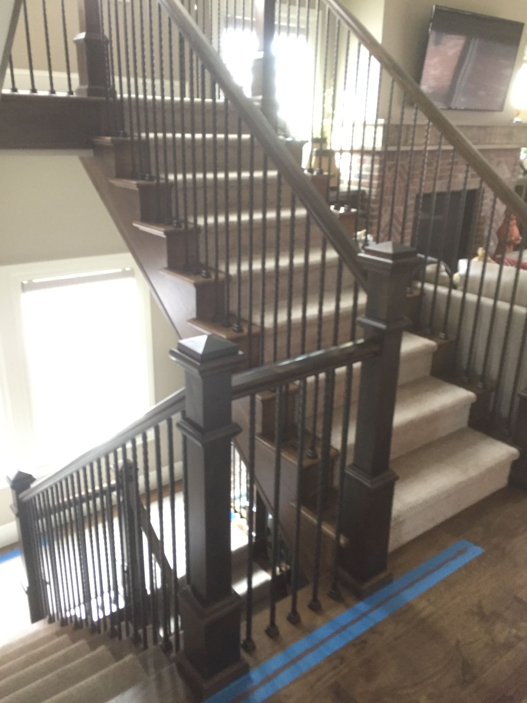 Staircase with dark wooden banisters and light carpeted steps. Wooden posts support the railing.