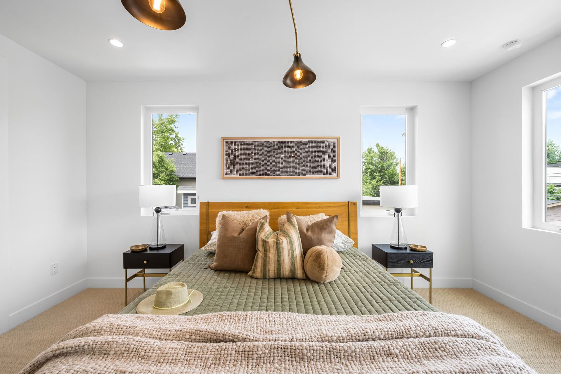 Bedroom with bed, nightstands, windows, and decorative pillows.