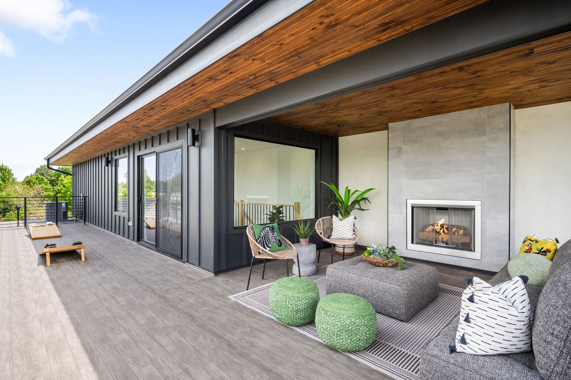 Outdoor living space with gray deck, fireplace, and seating under a wood-paneled ceiling.