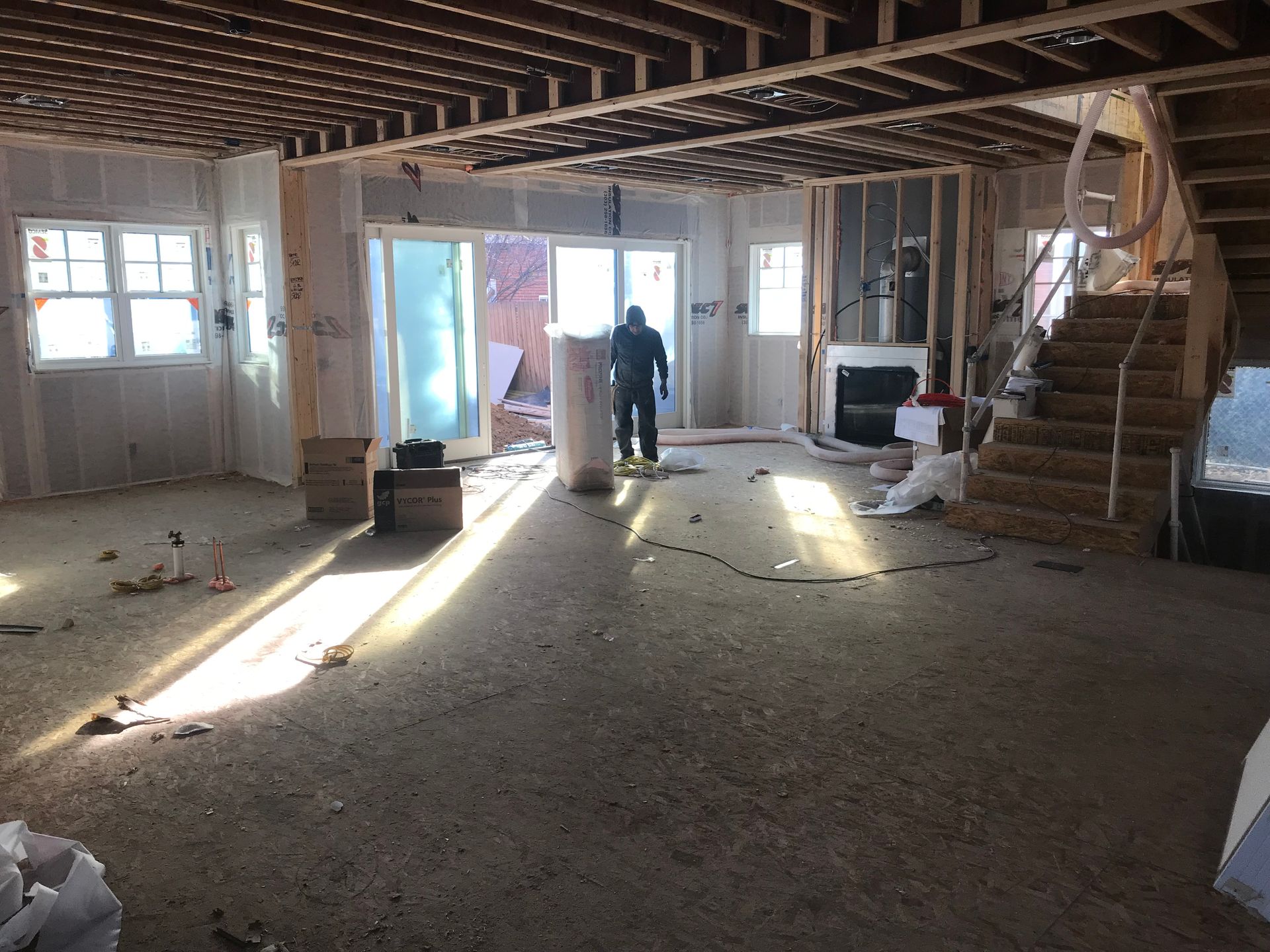 Interior of a building under construction. A person stands near a support column. Sunlight streams in.