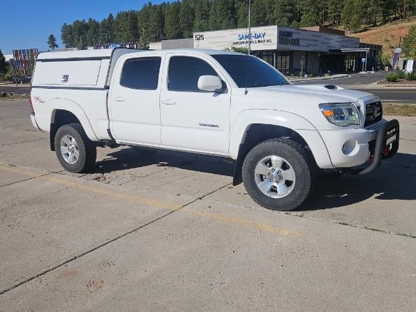 A red semi-truck with a white trailer parked on asphalt in a lot, with a dark blue semi in the background.