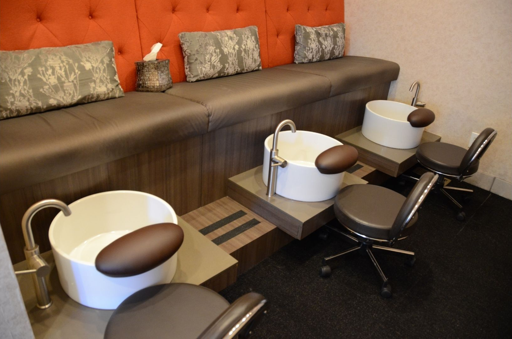 Feet and hands with fresh French manicures, surrounded by spa-like elements: candles, flowers, and nail polish.