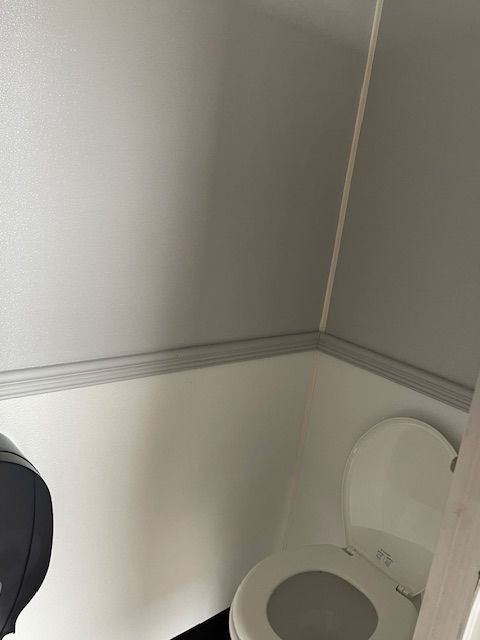 Restroom trailer urinal with towel dispenser.