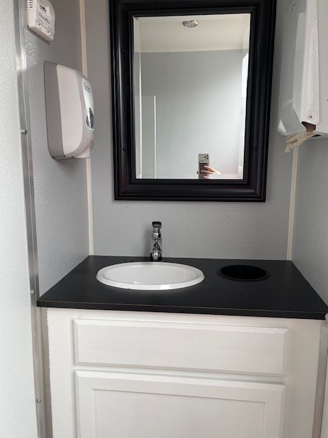 Restroom trailer with a sink and a mirror.