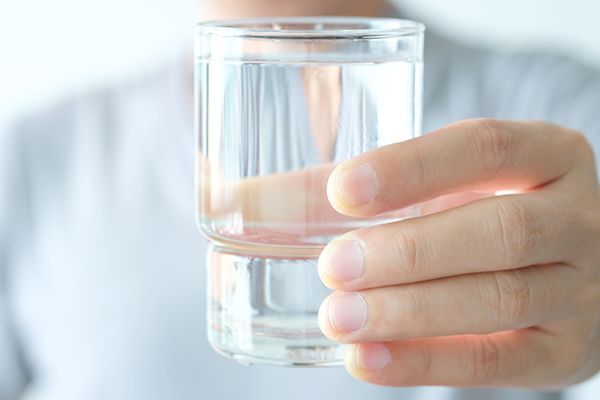a person is holding a glass of water in their hand 