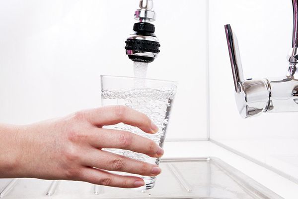 a person is pouring water into a glass from a faucet 