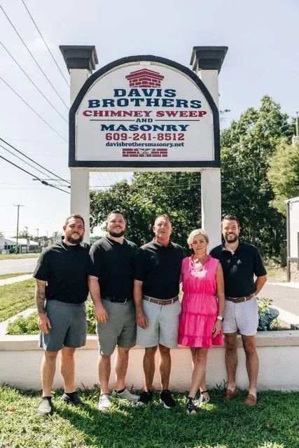 Five people in front of a sign for Davis Brothers Chimney Sweep and Masonry.