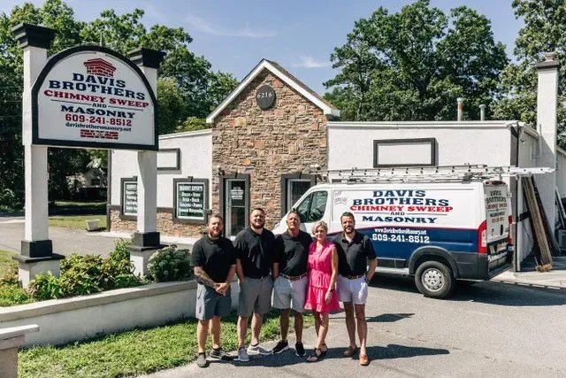 Davis Brothers Chimney Sweep and Masonry crew posing in front of their business; van parked nearby.