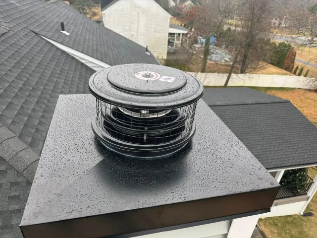 Black chimney cap with a spinning top on a black rooftop.