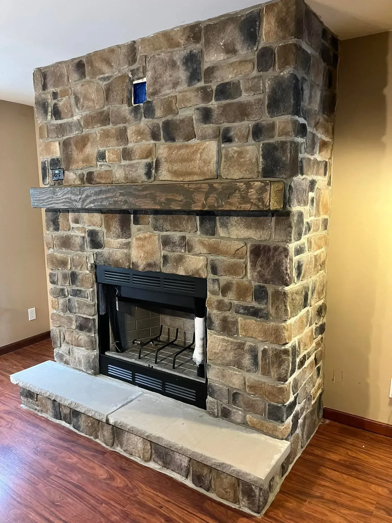 Stone fireplace with black firebox, gray hearth, and wood mantel.