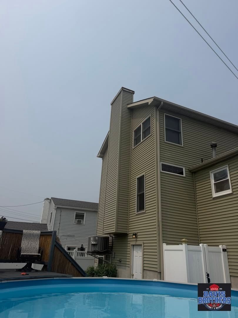 Backyard with blue pool and beige house under overcast sky