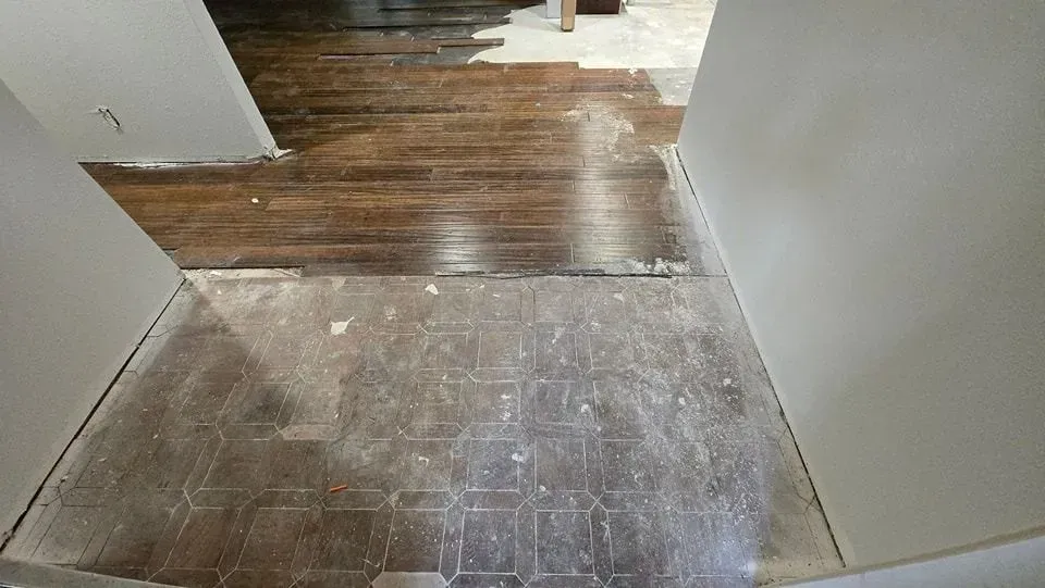 Hallway under renovation with dark wood floor and light tile floor. White walls.