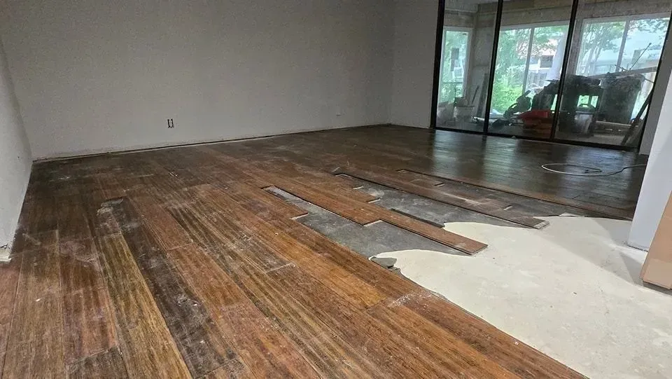 Room with partially removed wood flooring; concrete subfloor exposed.